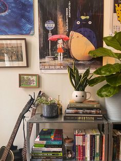 a shelf with books, plants and other items on it in front of a wall