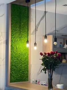 a vase filled with red roses sitting on top of a counter next to a green wall