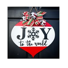 a joy to the world ornament hanging on a black door with red, white and green ribbon