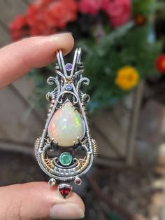 "Fire Opal Wire Wrapped Pendant This is hands down the finest opal I've ever set into a piece to date. I tried my best to capture the stone, but photos hardly do it justice B A L A N C E C O L L E C T I O N \"Striving to find equilibrium in all aspects of life\" D E T A I L S MATERIALS 1x Fire Opal (Welo Opal, Ethiopia) 4x Sapphire (B,Y,O) 1x Amethyst 1x Emerald 1x Garnet METALS .925 Sterling Silver 14k Gold-filled DIMENSIONS 2.5 x 1.1\" S T O N E M E A N I N G S OPALS are known to spark optimis Handmade Ethiopian Opal Elegant Jewelry, Silver Multi-stone Ethiopian Opal Jewelry, Unique Ethiopian Opal Gemstone Jewelry, Ethiopian Opal Gemstone Jewelry For Jewelry Making, Handmade Ethiopian Opal Jewelry For Anniversary, Handmade White Ethiopian Opal Jewelry, Unique White Jewelry With Gemstone Accents, Unique White Multi-stone Jewelry, Handmade Ethiopian Opal Pendant Jewelry