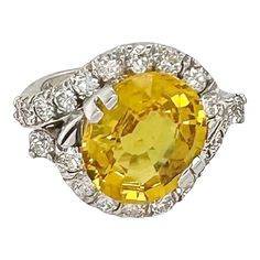 This is part of Chairish’s Fine Jewelry assortment.  Large yellow sapphire set in 14k white gold with a diamond surround. The yellow sapphire oval is approximately 7.1 carats measuring 13.6 x 12 x 6.7 mm while the 22 diamonds measure approximately 2.5mm each and equal 1.32 ctw.  This cocktail ring is in very good original condition with wear consistent with age and use.  Dimensions: 1” width, .75” depth, .25” height Ring size: 5 1/2 Fine Yellow Oval Sapphire Ring, Elegant Yellow Oval Sapphire Ring, Oval Yellow Sapphire Diamond Ring Fine Jewelry, Yellow Sapphire Oval Diamond Ring, Oval Yellow Sapphire Ring In Yellow Gold, Yellow Oval Sapphire Ring With Prong Setting, Yellow Oval Sapphire Diamond Ring, Oval Yellow Sapphire Ring With Diamonds, Luxury Yellow Oval Sapphire Ring