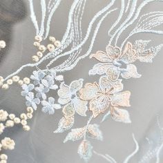 an embroidered fabric with flowers and leaves is shown in this close up photo, it appears to be very delicate