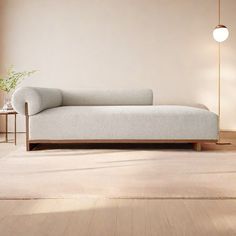 a white couch sitting on top of a wooden floor next to a table and lamp