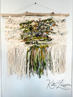 the wall hanging is made out of white yarn and has many different colored flowers on it