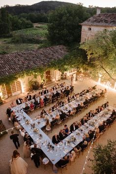 an aerial view of a wedding reception in the countryside at dusk with guests seated on tables