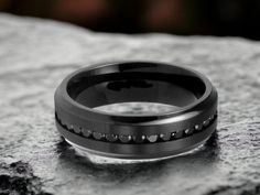 a black ring with white dots on it sitting on top of a stone slab in the sun