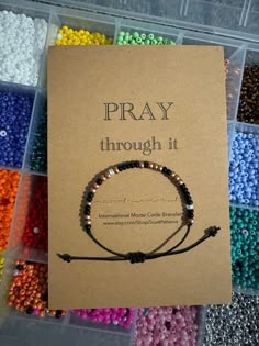 a box filled with lots of beads next to a card that says pray through it