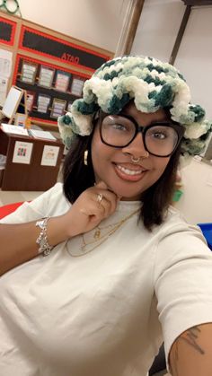 a woman with glasses and a flowered hat on her head is posing for the camera