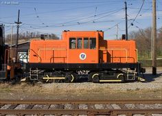 an orange train car sitting on the tracks