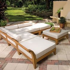 a couch and ottoman sitting on top of a stone patio floor next to a potted plant