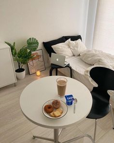 a white table topped with donuts and a cup of coffee next to a bed