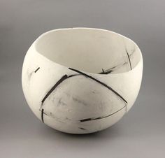 a white bowl sitting on top of a gray table next to a black and white object