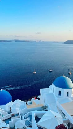 some white buildings and blue domes on the water