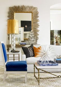 a living room filled with white furniture and colorful pillows on top of each other in front of a mirror