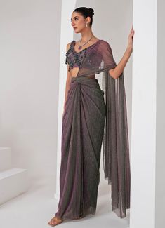 Elevate your style with the exquisite Lavender Pre Draped Crepe Saree, meticulously crafted from a luxurious platinoir crepe. The lavender saree shimmers with a subtle metallic tone, adding a touch of contemporary elegance to the traditional silhouette. Paired with a sleeveless V-neck blouse, this ensemble showcases intricate tonal crystal tassel and cutdana embellishments, creating a perfect blend of modern flair and classic grace. The pre-draped design ensures effortless wear, making it an ideal choice for those who desire both sophistication and convenience. Whether you're attending a Cocktails, Sangeet nights or a glamorous evening event, this saree promises to make a statement, reflecting your impeccable taste and style. Composition : Blouse - Crepe blend, Saree - Platinoir Crepe Care Fusion Style Pre-draped Saree With Unstitched Blouse, Elegant Purple Pre-draped Saree, Festive Formal Pre-draped Saree, Fusion Style Pre-draped Saree For Diwali, Diwali Fusion Style Pre-draped Saree, Evening Saree With Sheer Dupatta And Side Open, Fusion Style Silk Pre-draped Saree For Wedding, Fusion Style Pre-draped Saree With Zari Work, Purple Georgette Pre-draped Saree For Evening