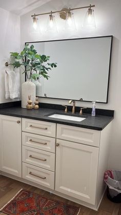 a bathroom vanity with a large mirror above it and a rug on the floor next to it