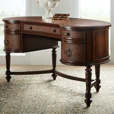 a wooden desk with drawers on top of it in front of a vase and window