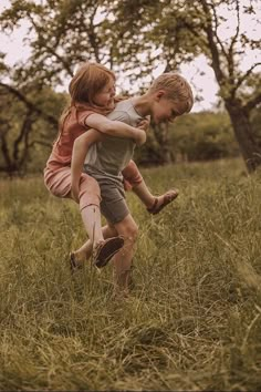 two children are playing in the grass with each other and one is holding onto another child's leg