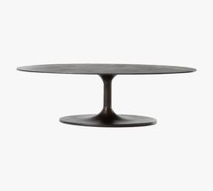 an oval dining table with black metal base and round top, against a white background