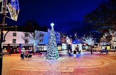 a christmas tree is lit up in the middle of a town square