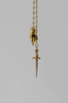 A fixed lariat style necklace made with an 18k gold-filled drawn cable chain with two tiered hanging pendants. An 18k gold filled brass 3D hand pendant with eye emblem and rhinestone cuff playfully hangs just above a sterling silver sword as if the hand is reaching for the sword. This necklace has no closures and easily fits over the head with a 30" neck chain opening. Details: Lariat necklace with dagger & hand pendants 18k gold-filled drawn cable chain - 36" length 18k gold filled brass 3D han Medieval Accessories Jewellery, Adjustable Hand Cast Yellow Gold Jewelry, Adjustable Hand-cast Yellow Gold Jewelry, Hand Cast Gold Sterling Silver Jewelry, Hand Cast Sterling Silver Gold Jewelry, Brass Lariat Jewelry As A Gift, Brass Lariat Jewelry For Gifts, Unique Gold Long Drop Jewelry, Minimalist Hand Cast Brass Jewelry