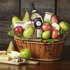 a wooden basket filled with lots of different types of fruit and cheese on top of a table