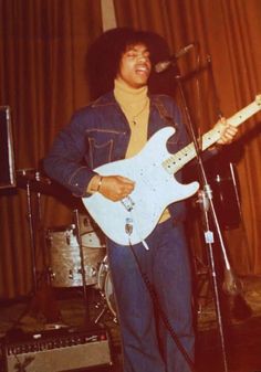 a man standing in front of a microphone and guitar