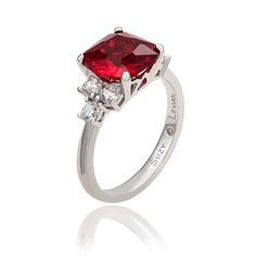 From the day he bends down on one knee through your 50th wedding anniversary and beyond, the sparkle in this gemstone ring will rival the sparkle in his eyes when he looks at you. Made of 925 sterling silver, this fabulous ring features a cushion cut red cubic zirconia center stone, sided by three white cubic zirconia's prong set on each side. If you are in the market for an affordable engagement ring that blends traditional with a dash of originality then this one is perfect for you. Every sing Red Brilliant Cut Cubic Zirconia Rings, Red Diamond Ring With Brilliant Cushion Cut, Red Diamond Princess Cut Ring, Red Cushion Cut Brilliant Diamond Ring, Red Cushion Cut Diamond Ring With Brilliant Cut, Red Princess Cut Diamond Ring, Formal Asscher Cut Ruby Ring With Center Stone, Red Brilliant Cut Birthstone Ring Fine Jewelry, Red Birthstone Ring With Brilliant Cut In Fine Jewelry