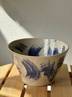 a blue and white bowl sitting on top of a wooden table next to a wall