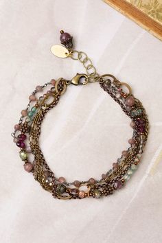 A stylish multistrand design, handcrafted with collage strands for a unique look. Antique Brass (lead and nickel free) Crystal, Lepidolite Quartz, Czech Glass 7.5-8.5", adjustable with an antique brass lobster claw clasp We hand select our natural materials, thus there may be slight variations in color and/or size that will not detract from the overall aesthetic Our unique handcrafted designer jewelry for women is made in America, with each design created individually in our personal design studio in Floyd VA USA Bohemian Brass Bracelets With Adjustable Chain, Nickel-free Adjustable Multi-strand Bracelets, Adjustable Multicolor Brass Bracelets, Adjustable Nickel-free Multi-strand Beaded Bracelets, Adjustable Multi-strand Nickel-free Beaded Bracelets, Bohemian Bracelets With Extender, Bohemian Adjustable Bracelets With Extender, Bohemian Multi-strand Nickel-free Bracelets, Bohemian Multi-strand Wire Wrapped Beaded Bracelets