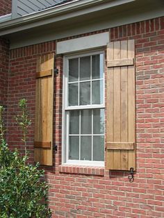 a red brick house with two windows and shutters