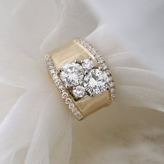 three stone diamond ring sitting on top of a white cloth with tulle in the background