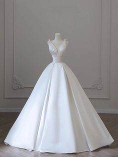 a white wedding dress on a mannequin stand in the middle of a room