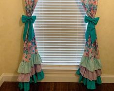 the window is decorated with colorful curtains and bowknots on it's valance