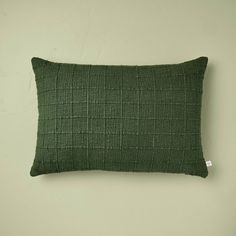 a green pillow sitting on top of a white wall