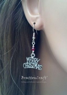 Merry Christmas! The charms on these Merry Christmas Earrings are made of lead free pewter in the USA with an antique silver finish. The red bead is Swarovski crystal and the small silver beads are silver plated. The earring is 7/8 inches wide at the bottom and the earring is 1 inch long from the end of the ear wire. The ear wire shown is stainless steel. Sterling silver ear wires with the same style are available and may be selected at checkout. Plastic earring backs are included. These festive Silver Christmas Holiday Jewelry, Nickel-free Christmas Party Jewelry, Holiday Silver Jewelry With Ear Wire, Silver Jewelry For New Year Holiday, Adjustable Silver Christmas Earrings, Nickel-free Silver Earrings For Christmas, Nickel Free Silver Earrings For Christmas, Adjustable Sterling Silver Christmas Jewelry, Nickel-free Dangle Jewelry For Christmas