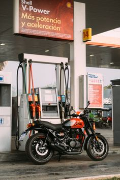 a motorcycle is parked in front of a gas station with an open fuel pump and sign that says shell v - power mas potendio y'allelection