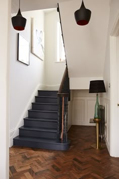 the stairs in this house are made of wood and have black lamps hanging from them