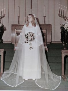 an old photo of a woman wearing a wedding dress and holding a bouquet in front of her