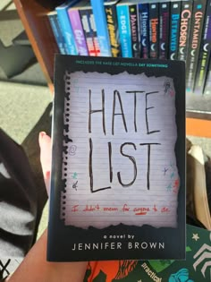 someone holding up a book with the title hate list written on it