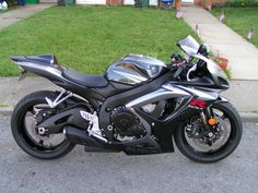 a silver and black motorcycle parked in front of a house on the side of the road