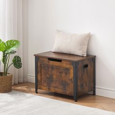 a wooden box with a cushion on top next to a potted plant