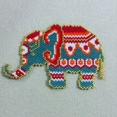 an elephant is made out of beads on a white surface with red and blue accents