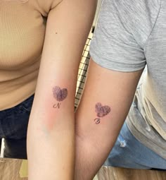 two people with matching tattoos on their arms, one is holding the other's arm