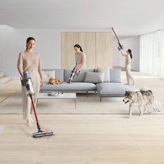 two women and a dog are in the living room with vacuums on the floor