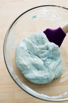 a wooden spoon in a glass bowl filled with blue food