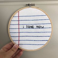 someone is holding up a cross - stitch hoop with the words i love you on it