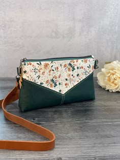 a green and white purse sitting on top of a wooden table next to a flower