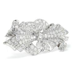 Description: This vintage Art Deco platinum brooch has been exquisitely crafted and cared for. This piece has been molded into a sensuous ribbon inspired motif exhibiting multiple layers of fabric blooming from its center. The brooch's surface is completely encrusted with natural diamonds. There are a total of 132 diamonds weighing approximately 5.00 carats total. There is a methodical mixture of baguette, single and old mine cut diamonds which are bead set, channel set and bezel set displaying Elegant Platinum Wedding Brooches, Elegant Brilliant Cut Brooches For Anniversary, Elegant Platinum Brooches For Gift, Elegant Wedding Platinum Brooches, Formal White Gold Platinum Brooches, Classic White Gold Brooches For Evening, White Brilliant Cut Brooches For Wedding, Elegant Platinum Brooch For Anniversary, Elegant White Gold Brooches For Evening