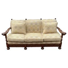 an old fashioned couch with two pillows on it's back and armrests